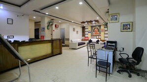A reception area with a wooden desk, white sofas, and a computer desk with a laptop.