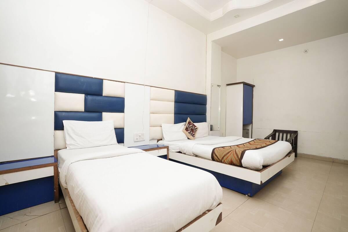 A hotel room with two beds, a large mirror, and a wardrobe.