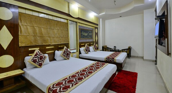 A hotel room with two beds, a red rug, and a TV mounted on the wall.
