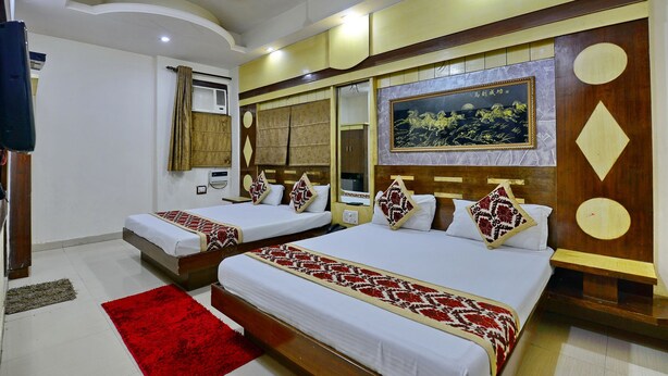 A hotel room with two beds, a red rug, and a large painting on the wall.