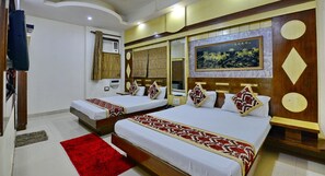 A hotel room with two beds, a red rug, and a large painting on the wall. - Hotel Sai Dham International (New Delhi)