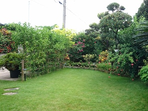 A lush garden with a variety of plants and flowers, a neatly trimmed lawn, and a wooden fence.