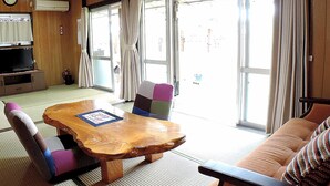 Une pièce de style japonais traditionnel, avec un sol recouvert de tatamis, une basse table en bois et un canapé agrémenté de coussins.