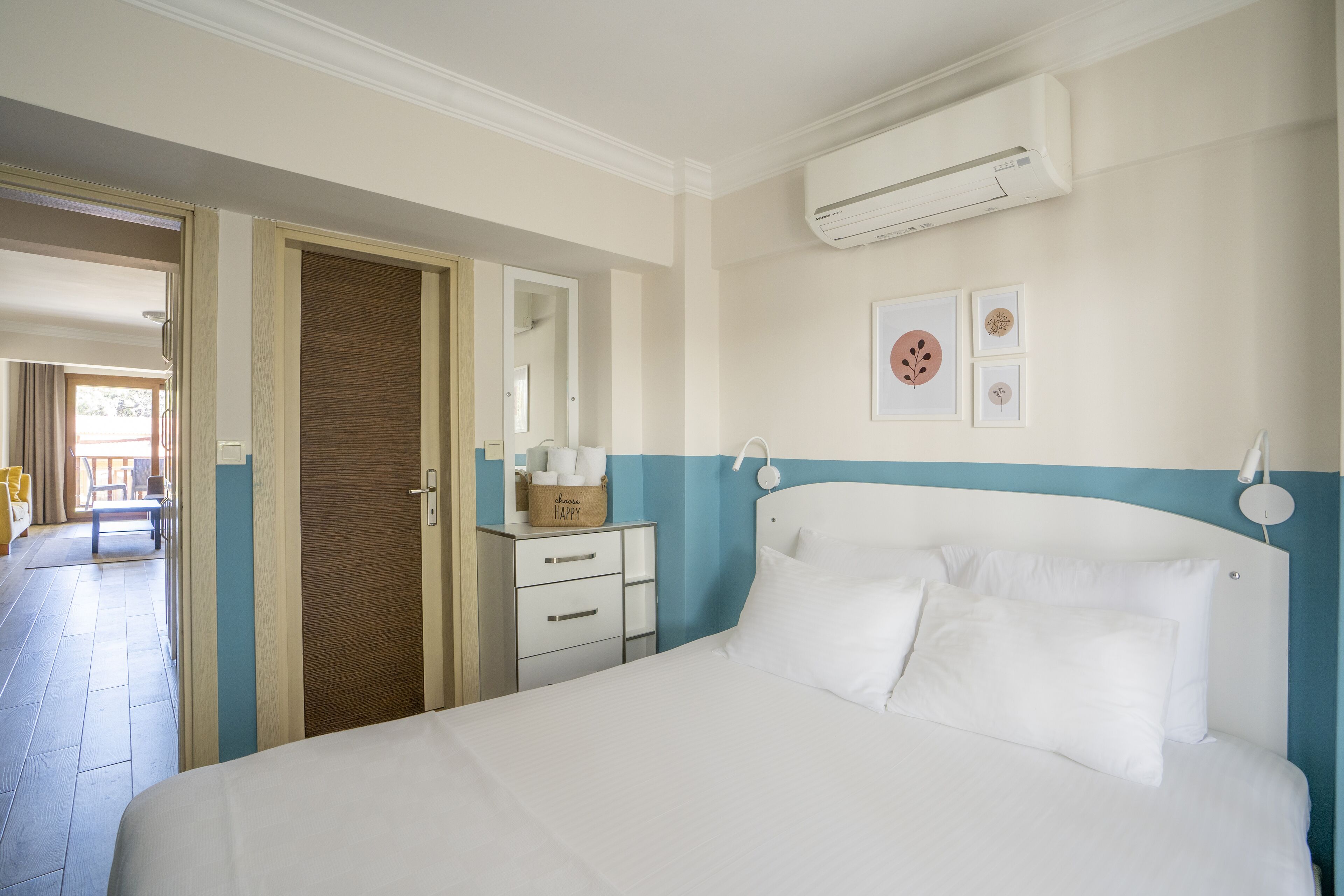A hotel room with a bed, a bedside table, a wardrobe, and an air conditioning unit on the wall.