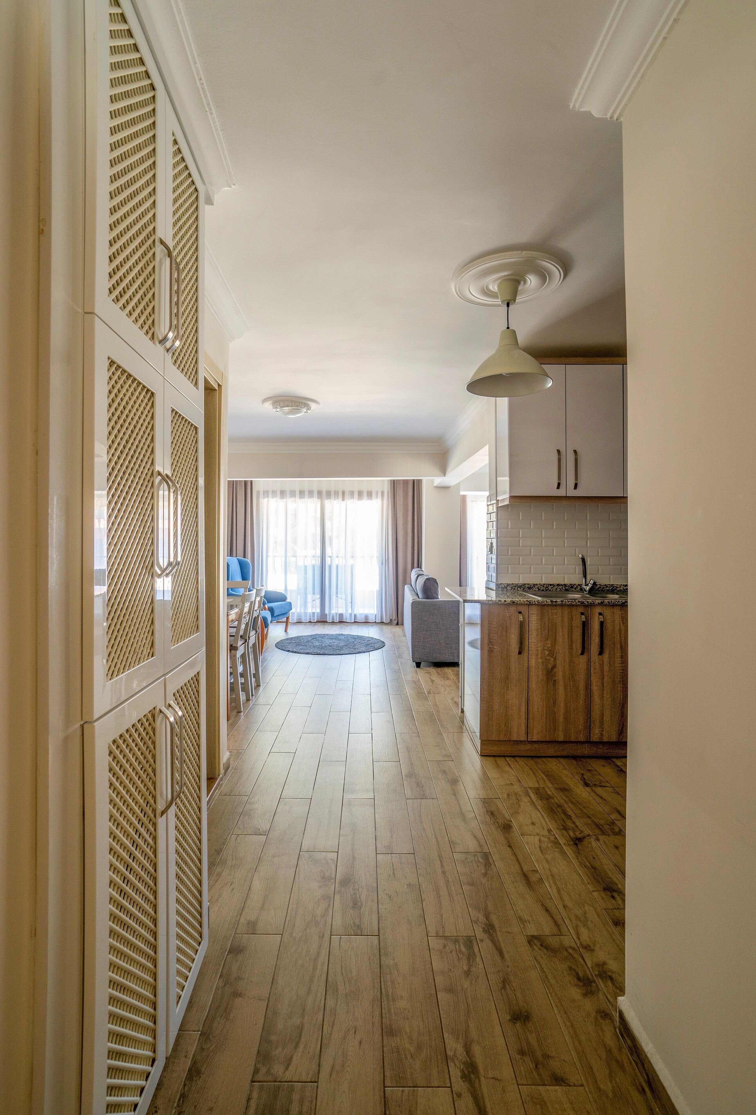 A spacious hallway with wooden flooring, a kitchen area with wooden cabinets, and a dining area with a round table and chairs.