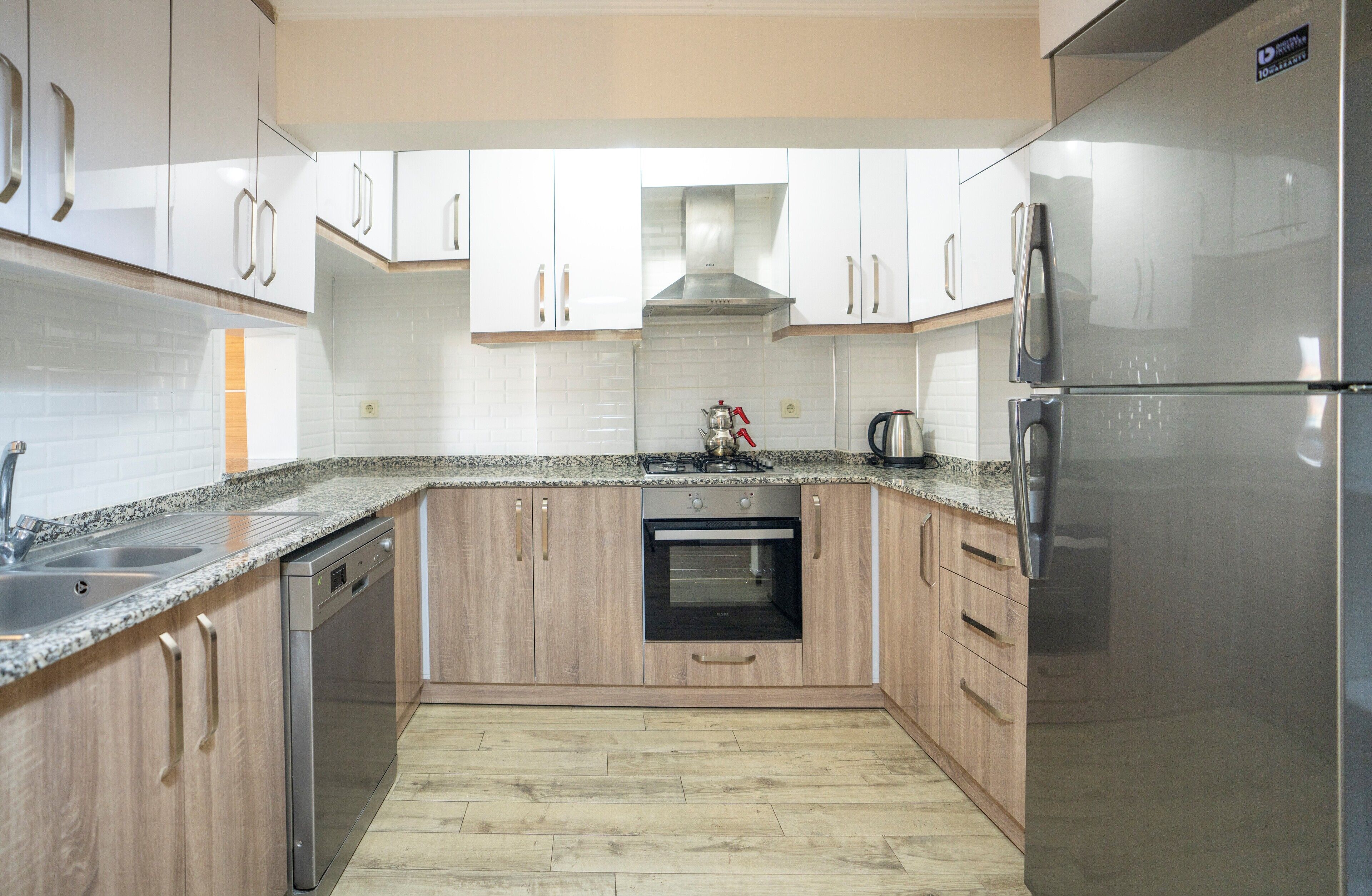 Una cocina moderna con armarios de madera, un refrigerador de acero inoxidable, un horno y un lavavajillas.