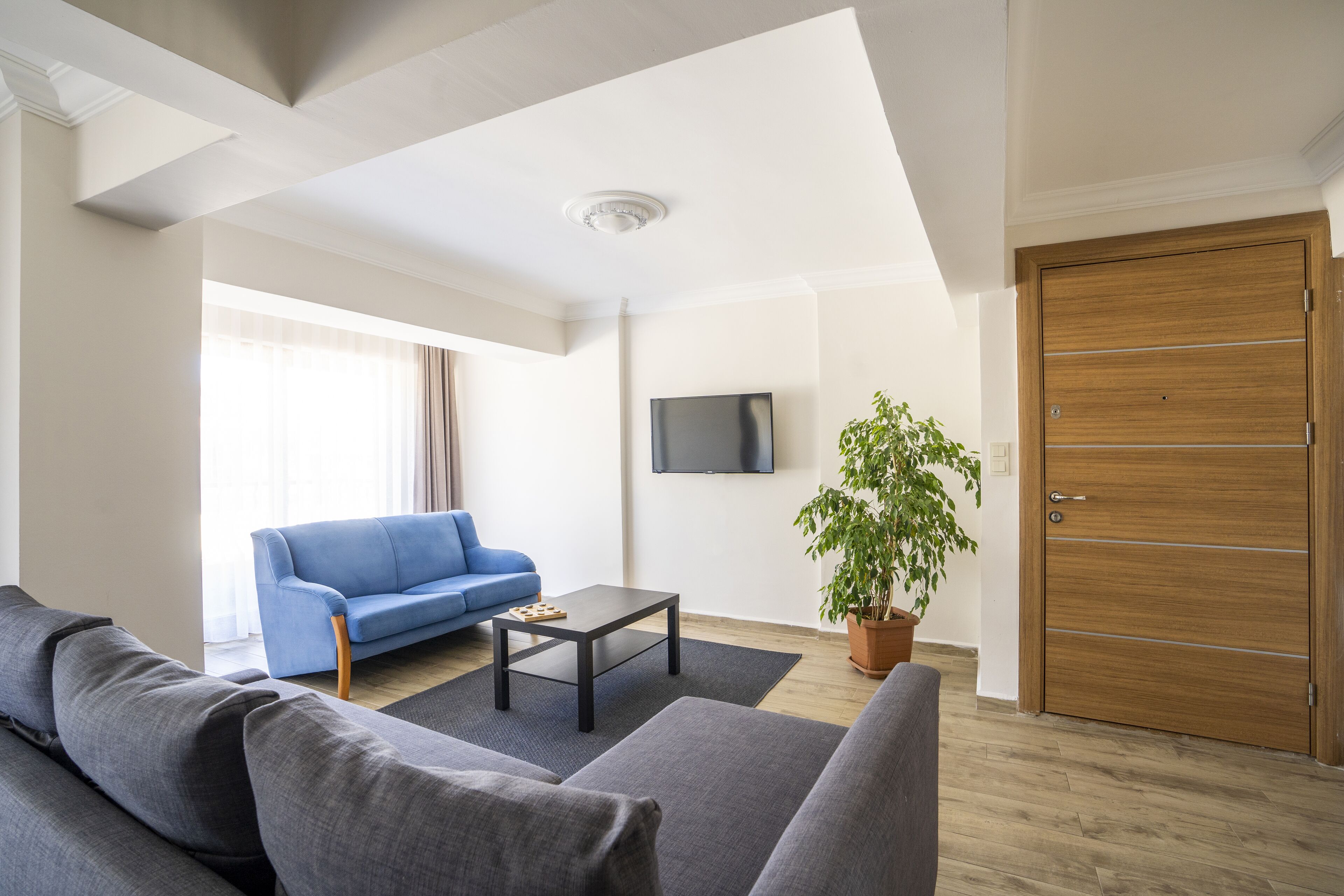 Un salon moderne avec un canapé bleu, un canapé gris, une table basse et une porte en bois.