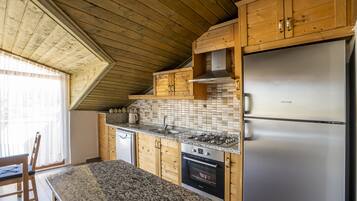 Eine Küche mit Holzausstattung, einem Edelstahlkühlschrank, einem Gasherd und einer gefliesten Spritzwand.