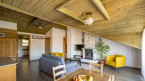 Un salon moderne avec un plafond en bois, une table à manger ornée de fruits, un canapé et un fauteuil jaune.