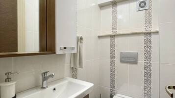 A modern bathroom with a white sink, mirror, and toilet.