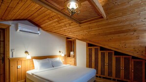 Une chambre avec un plafond en bois, un lit, une table de chevet, un climatiseur fixé au mur et des armoires en bois.