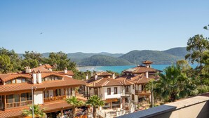 Un hôtel situé sur la côte, composé de plusieurs bâtiments, doté de balcons et offrant une vue sur la mer et les montagnes.