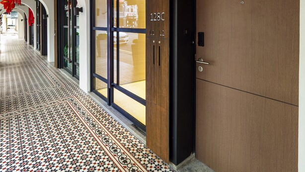Zona de recepción de un hotel con diseño moderno, que incluye un mostrador de recepción, una puerta de madera y un suelo con diseño.