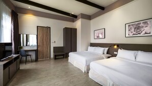 Habitación de hotel con dos camas, un escritorio, una silla y un ventanal con cortinas.