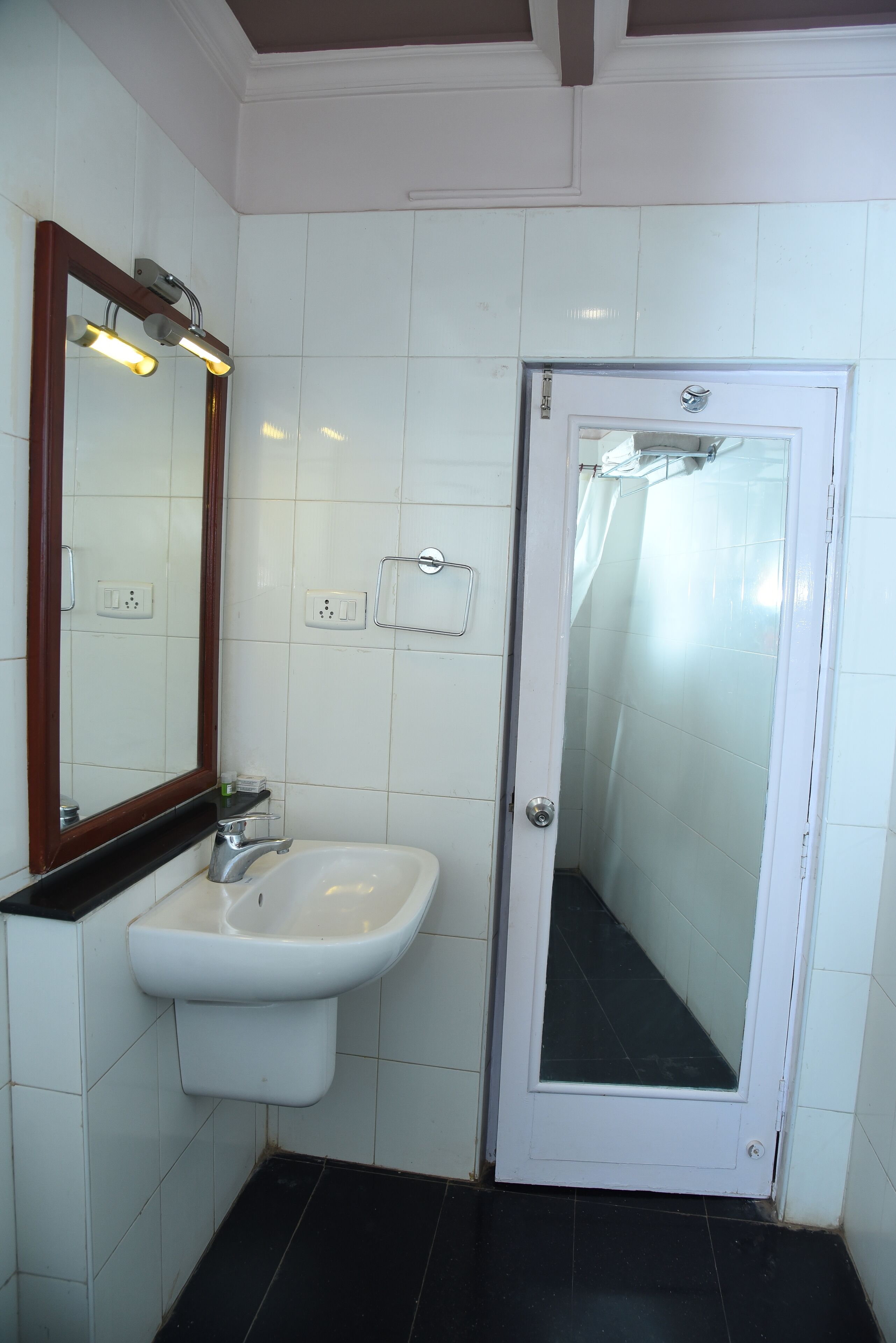 A bathroom with a white sink, a mirror, and a shower door.