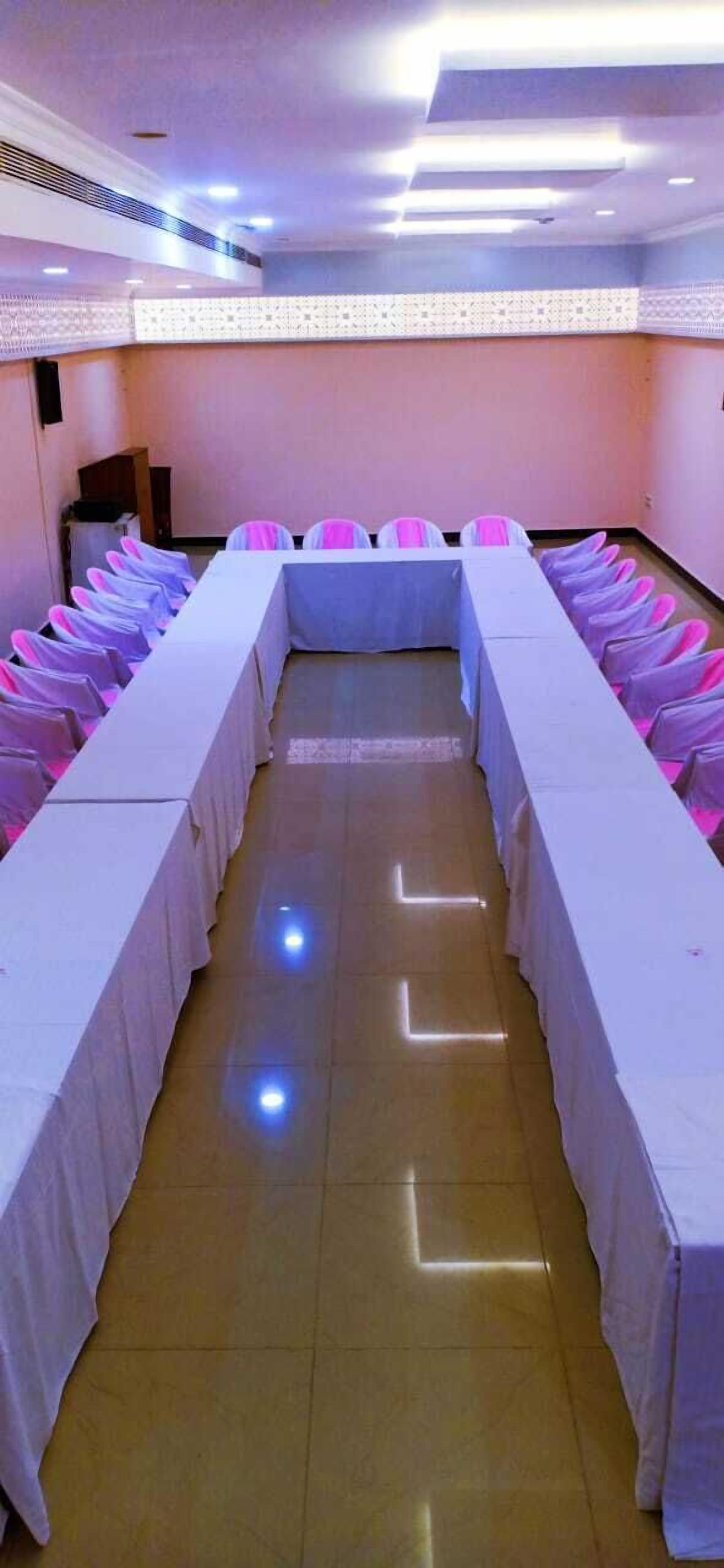Un salón de conferencias con una mesa larga, sillas y piso de baldosas.