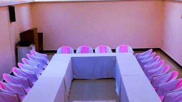 Un salón de conferencias con una mesa larga, sillas y piso de baldosas.
