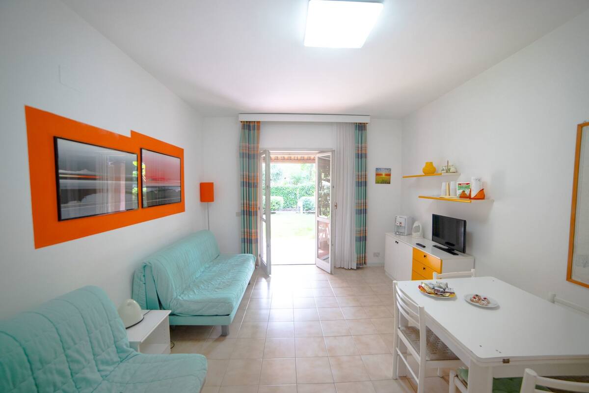 Ein Zimmer mit Bett, Schreibtisch, Stuhl, Fernseher und einem fensterbepflanzten Fenster.