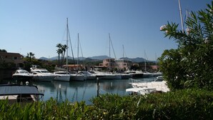 A marina with several boats docked, surrounded by greenery and buildings in the background. - Portorosa Residence (Furnari)