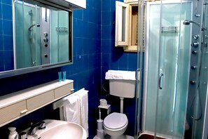 A bathroom with a glass-enclosed shower, a white sink, a toilet, and a mirror above the sink. - Portorosa Residence (Furnari)
