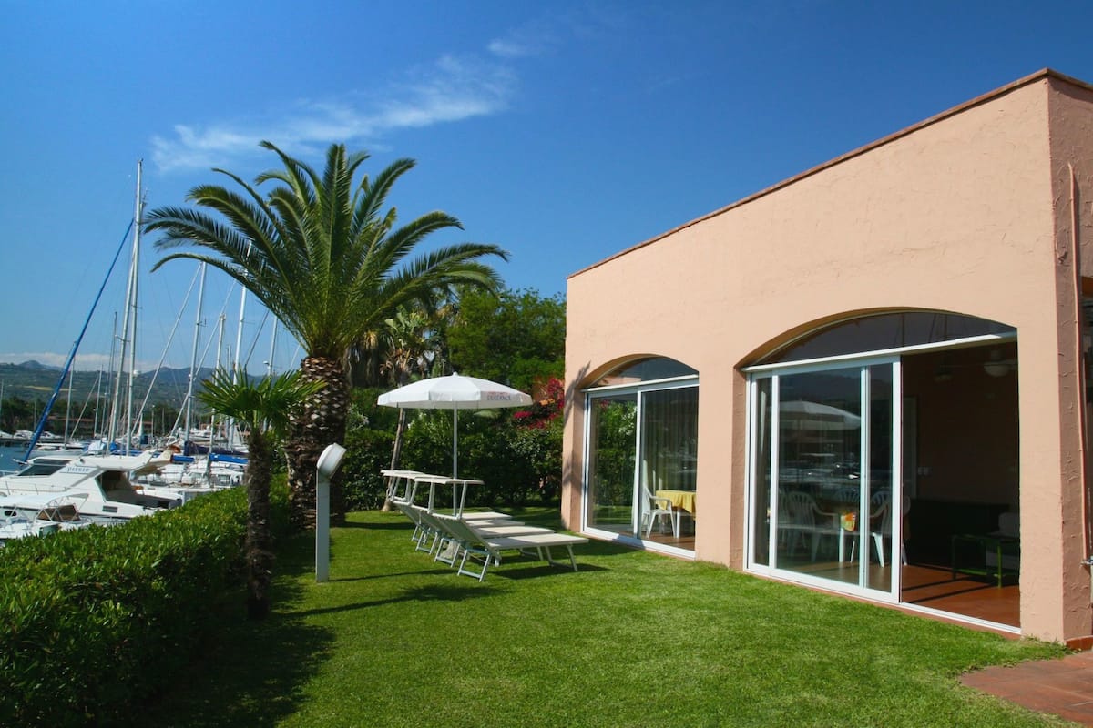 Ein modernes Gebäude mit großen Glasüren und einer Terrasse mit weißen Stühlen und einem Tisch.