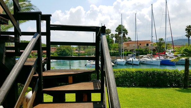 A wooden staircase leading to a terrace overlooking a marina with boats and greenery. - Portorosa Residence (Furnari)