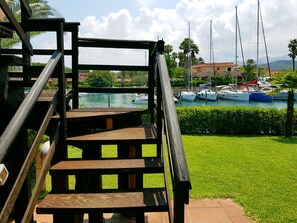 A wooden staircase leading to a terrace overlooking a marina with boats and greenery. - Portorosa Residence (Furnari)