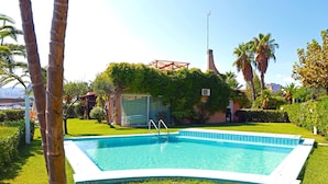 A rectangular swimming pool with a white edge, surrounded by well-maintained grass and palm trees. - Portorosa Residence (Furnari)