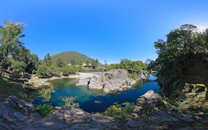 Un paisaje natural con un lago azul cristalino, terreno rocoso y una montaña al fondo.