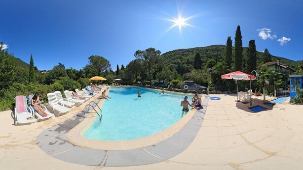 A swimming pool with lounge chairs and umbrellas, surrounded by greenery and hills. - Camping Valle Romantica (Cannobio)