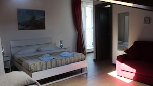 Un dormitorio con cama, una silla roja, una mesita de noche y una ventana con cortinas.