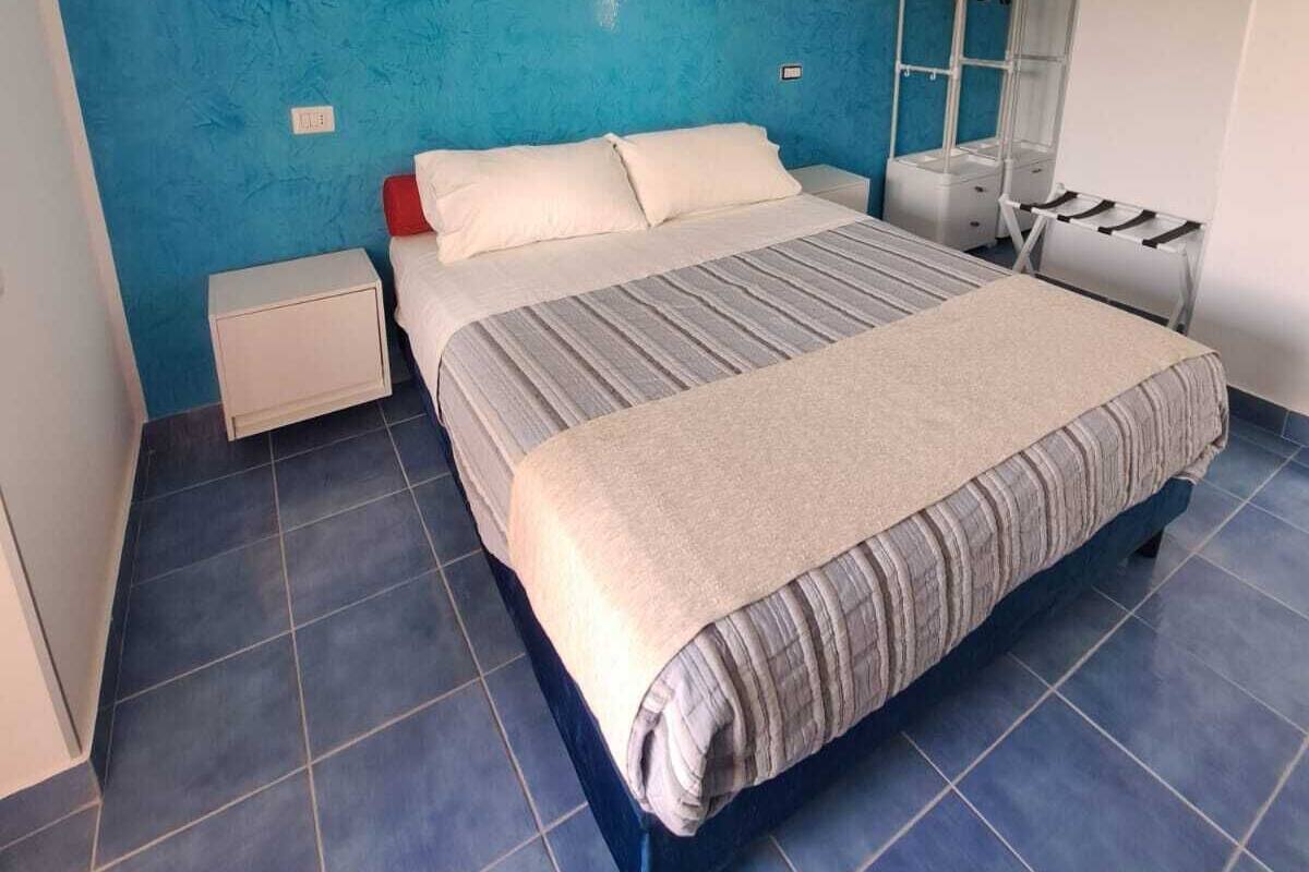 A bedroom with a bed, a nightstand, a mirror, and a wall with a painting.