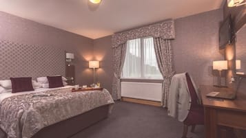 Une chambre d’hôtel avec un lit, des lampes de chevet, un bureau avec un ordinateur portable, une chaise et une fenêtre avec des rideaux.