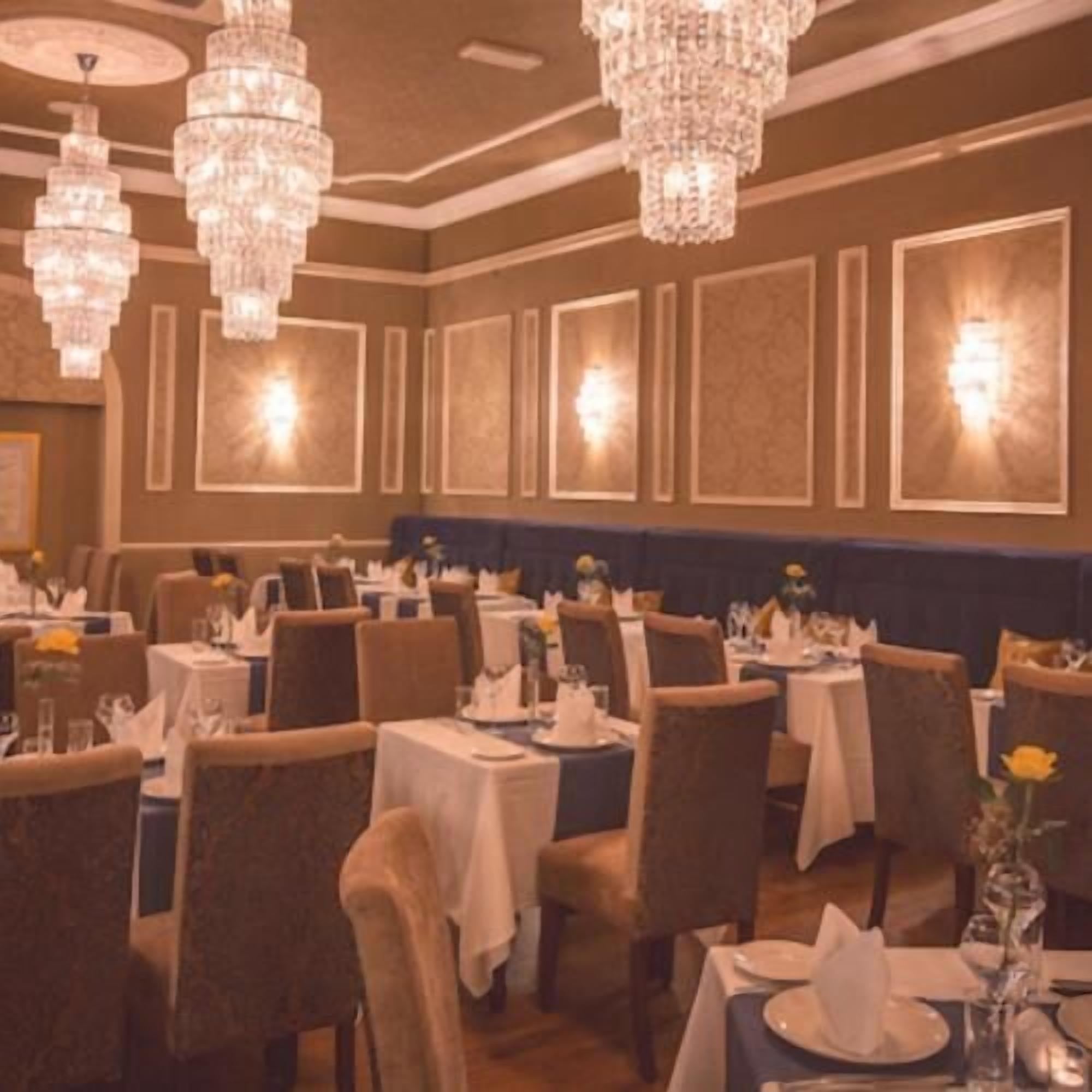 A restaurant with multiple tables, chairs, and chandeliers.