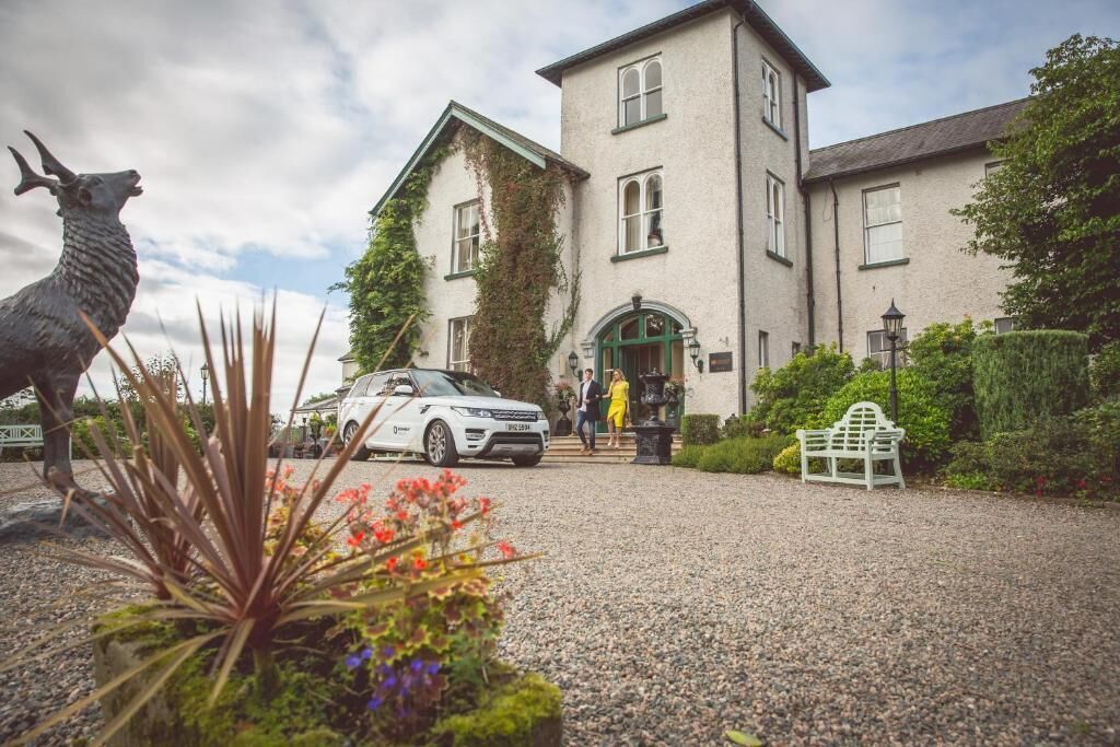 A building with a traditional architectural style, a gravel driveway, and a statue of a llama.