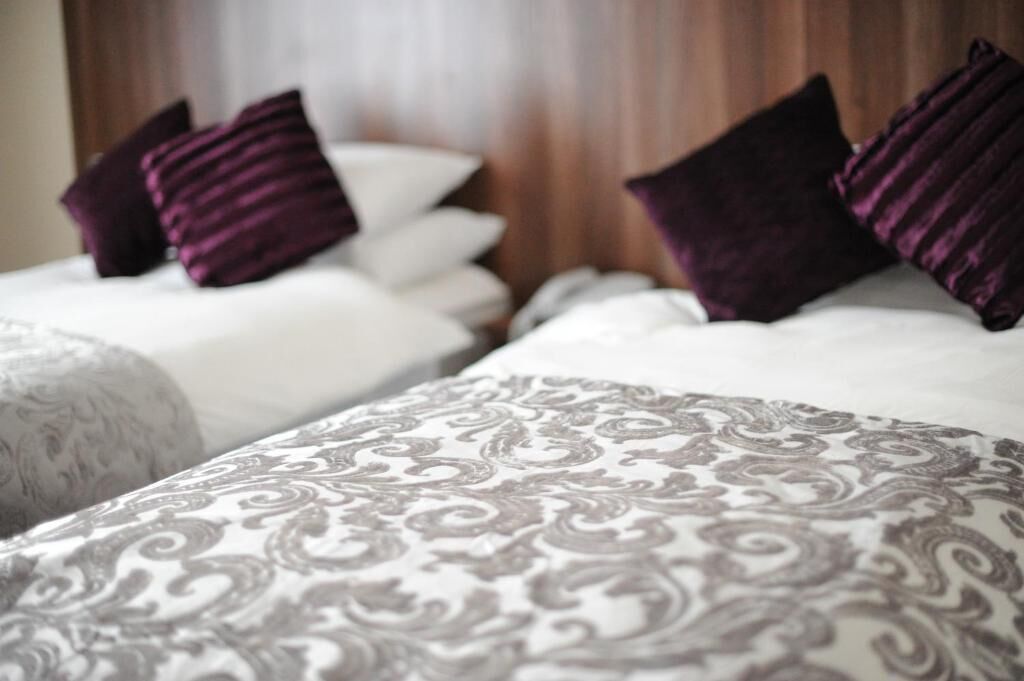Dos camas con ropa de cama estampada y almohadillas oscuras.