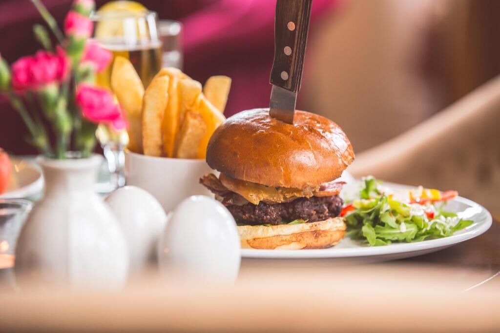 Una hamburguesa acompañada de papas fritas y una ensalada en un plato.