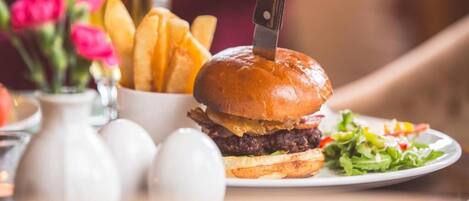 Una hamburguesa acompañada de papas fritas y una ensalada en un plato.