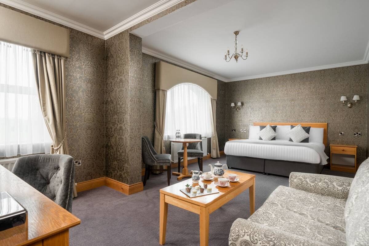 A hotel room with a bed, a sitting area with a table, a chair, and a sofa.