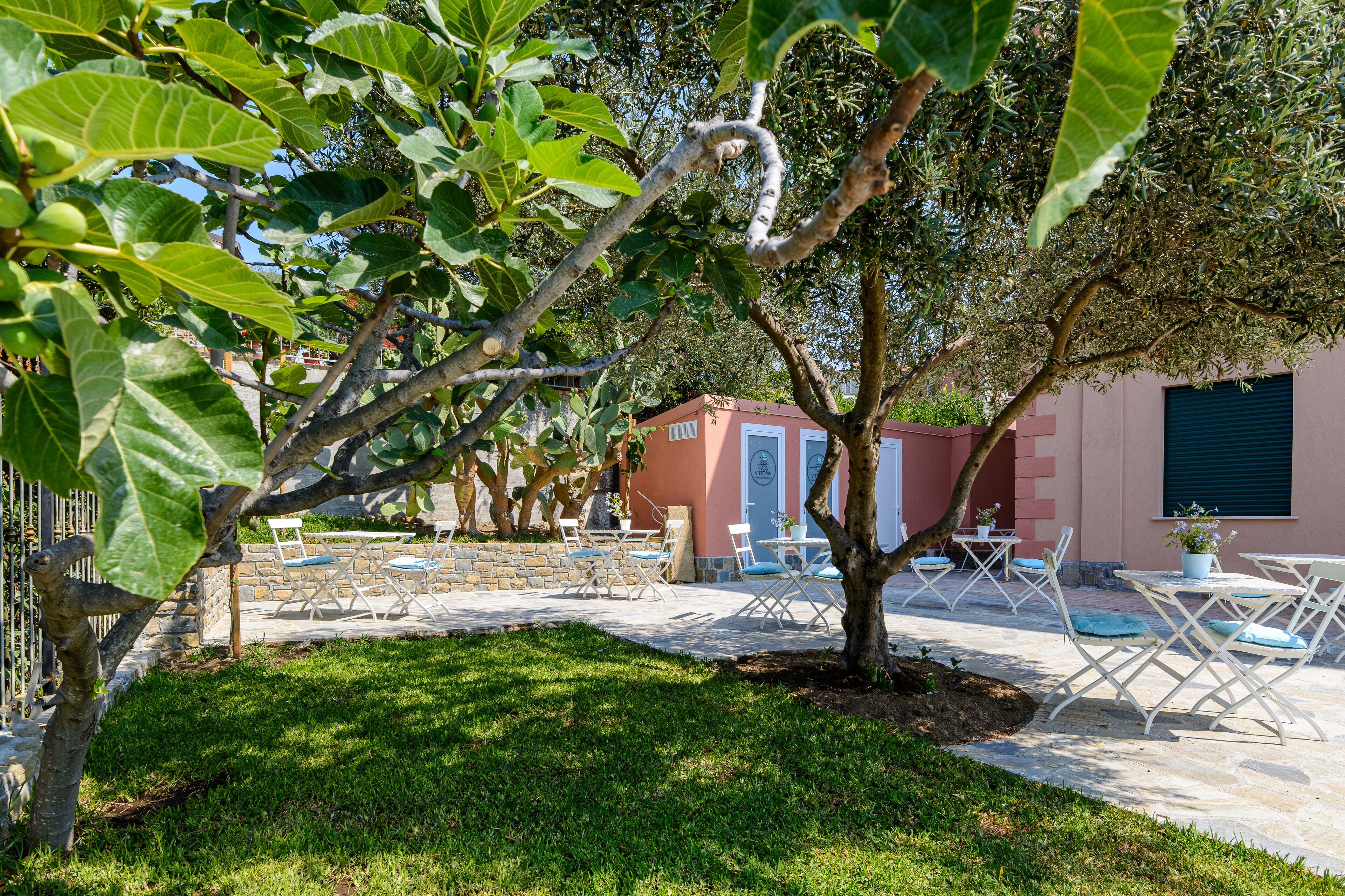 A patio area with outdoor furniture, a stone pathway, and a building with a pink facade.