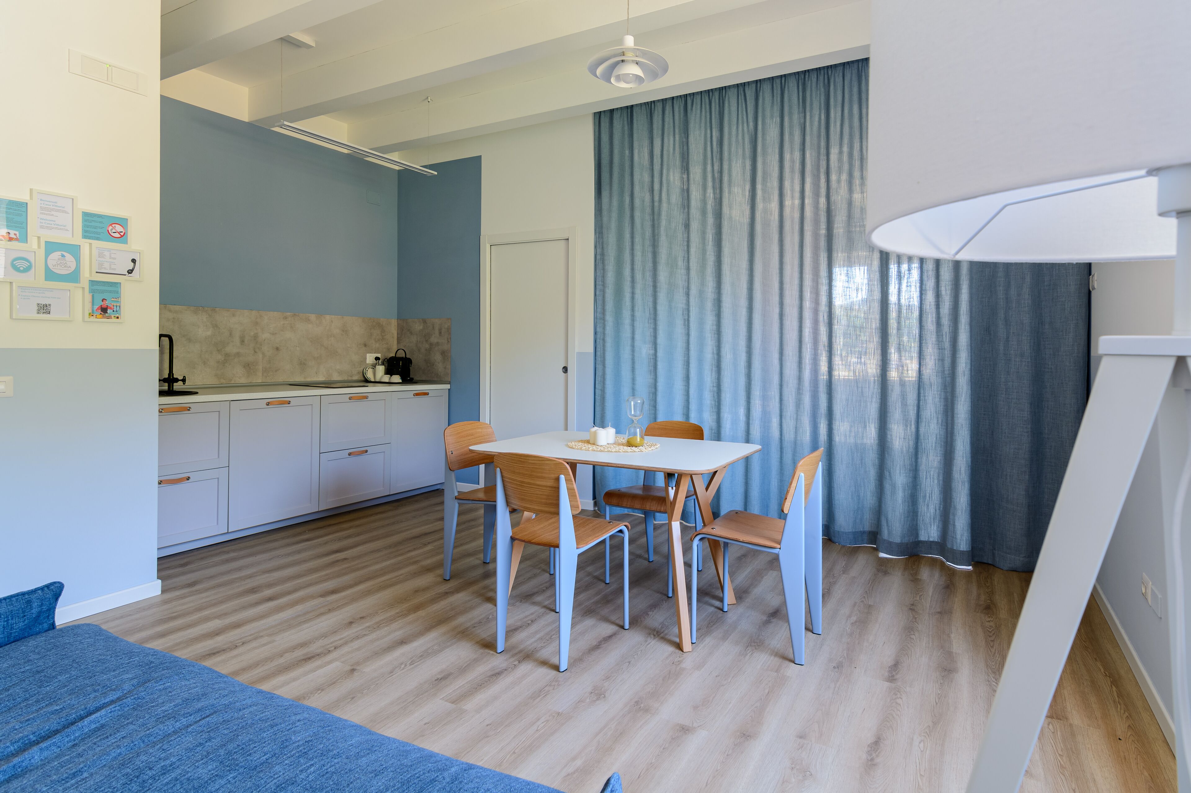 A modern, compact living space with a dining area, kitchenette, and a large window with curtains.
