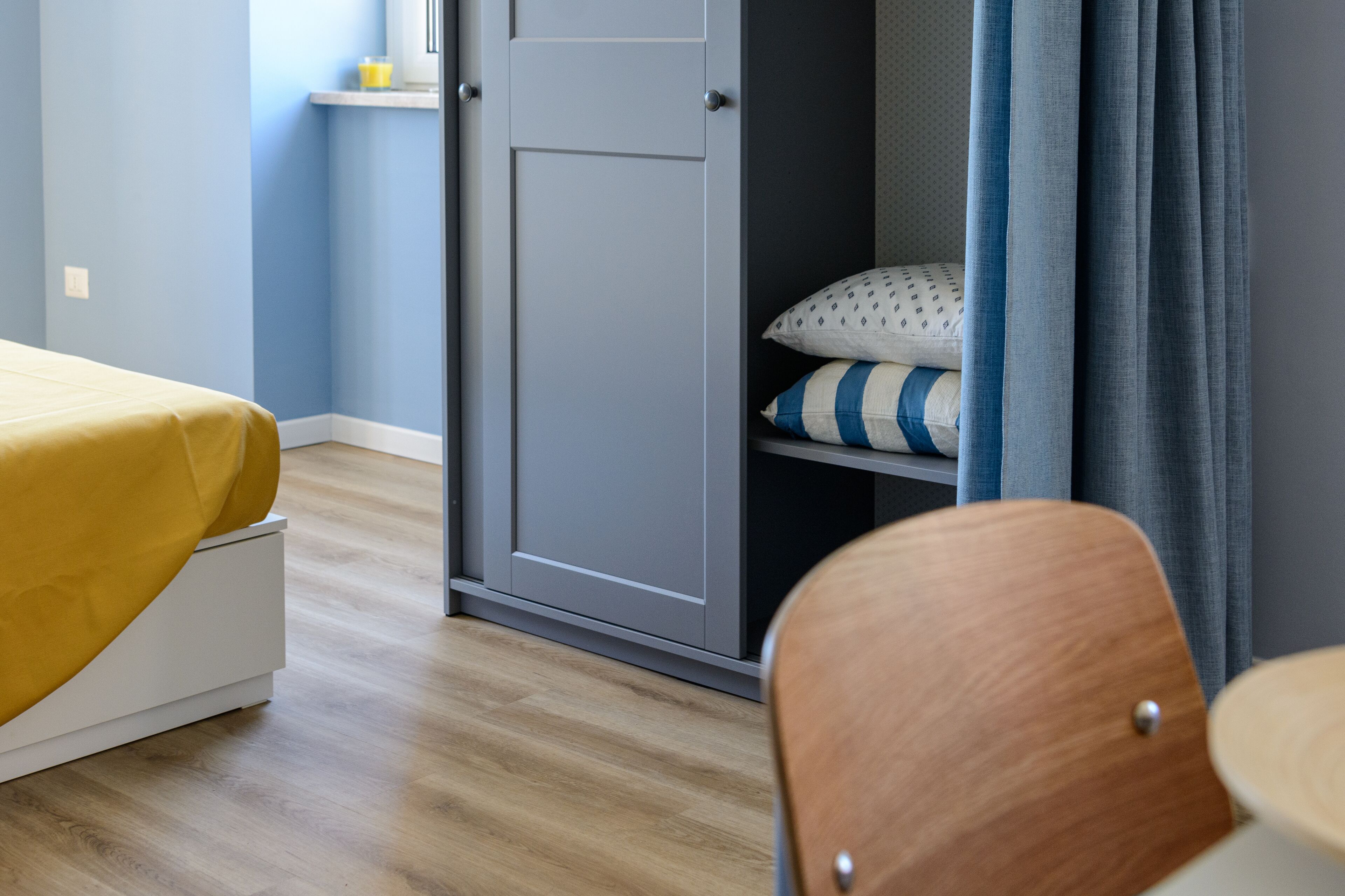 Un dormitorio con cama, armario y una silla.