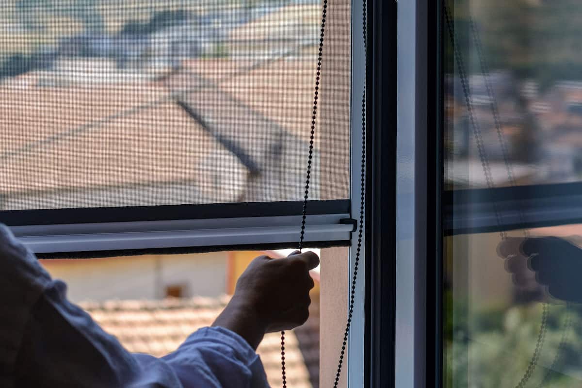 A hand adjusting a window blind.