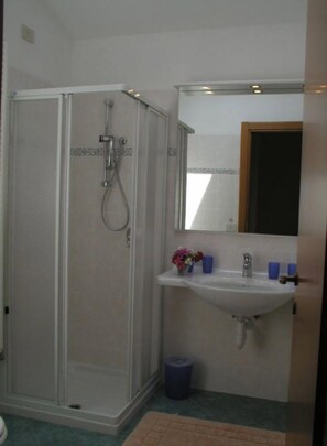 A bathroom with a walk-in shower, a sink with a mirror, and a trash bin. - Camping Riviera (Cannobio)