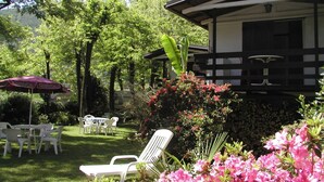 Un espacio patio con mobiliario exterior, una estructura cubierta y abundante vegetación.