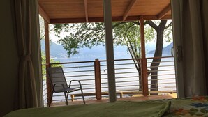 Una habitación con techo de madera, vistas a un lago, una silla y una cama con colcha estampada.