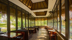Een restaurant met een lange toonbank, zitjes en grote ramen met uitzicht op het buitengebied.