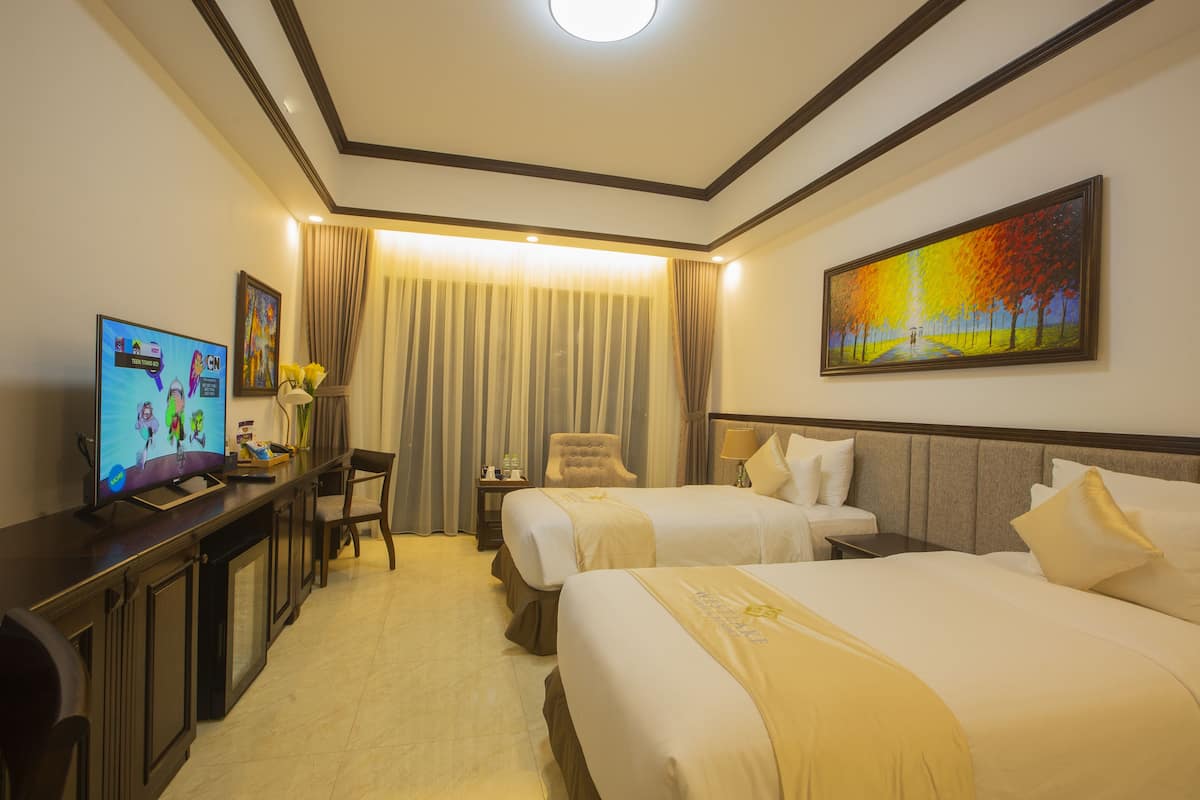 A hotel room with two beds, a desk with a TV, a chair, a nightstand, and a painting on the wall.