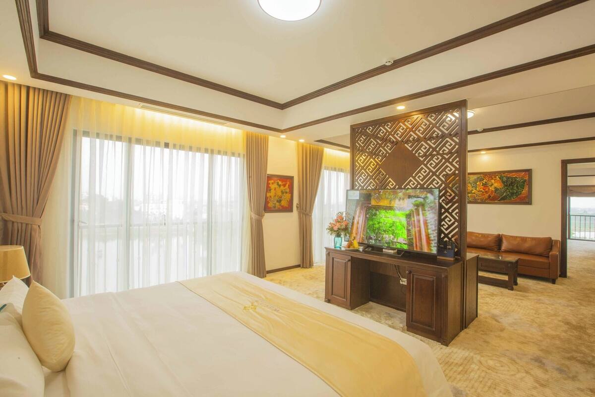 A hotel room with a large bed, a TV, a desk, and a sofa.
