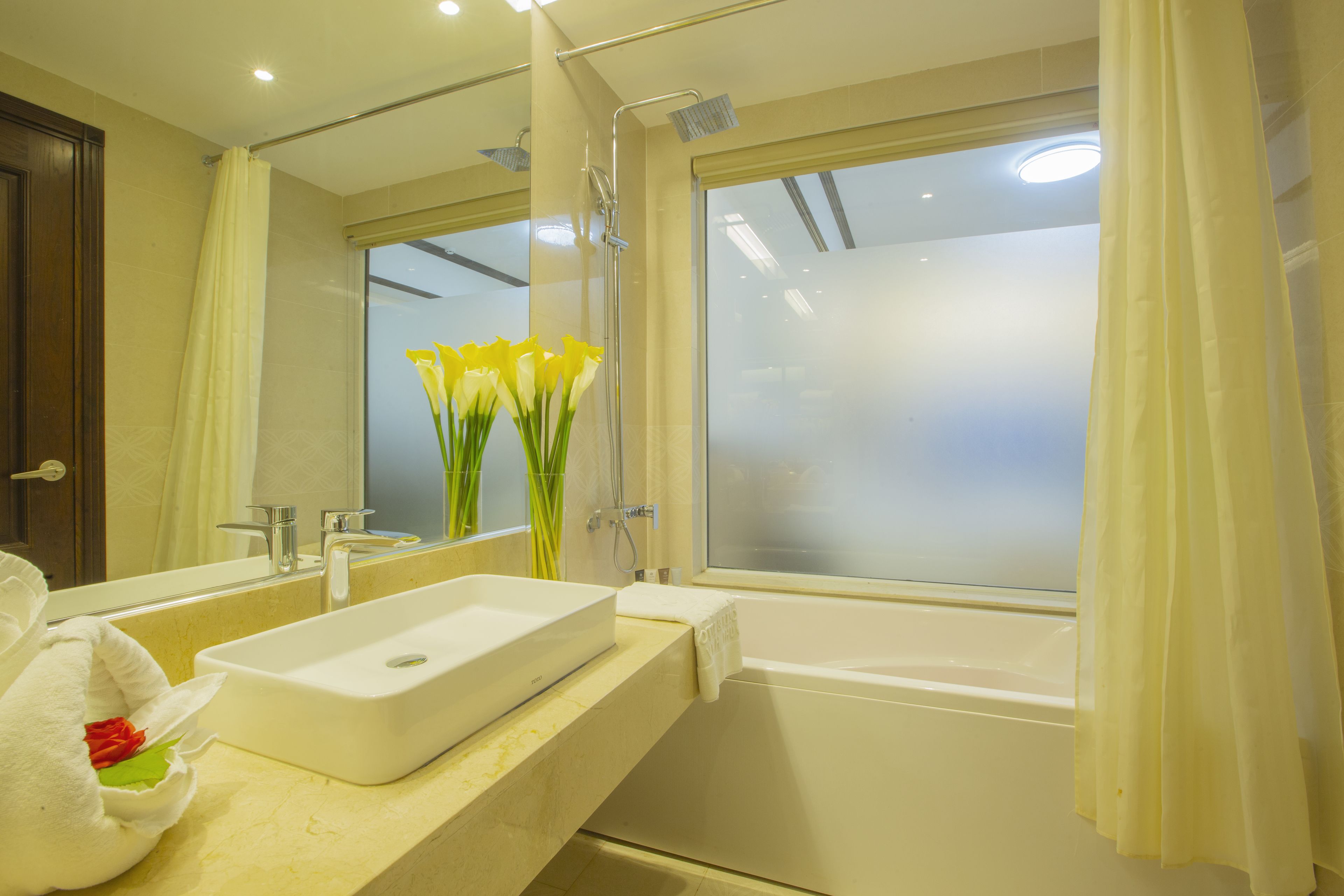 A bathroom with a large mirror, a bathtub, and a sink.